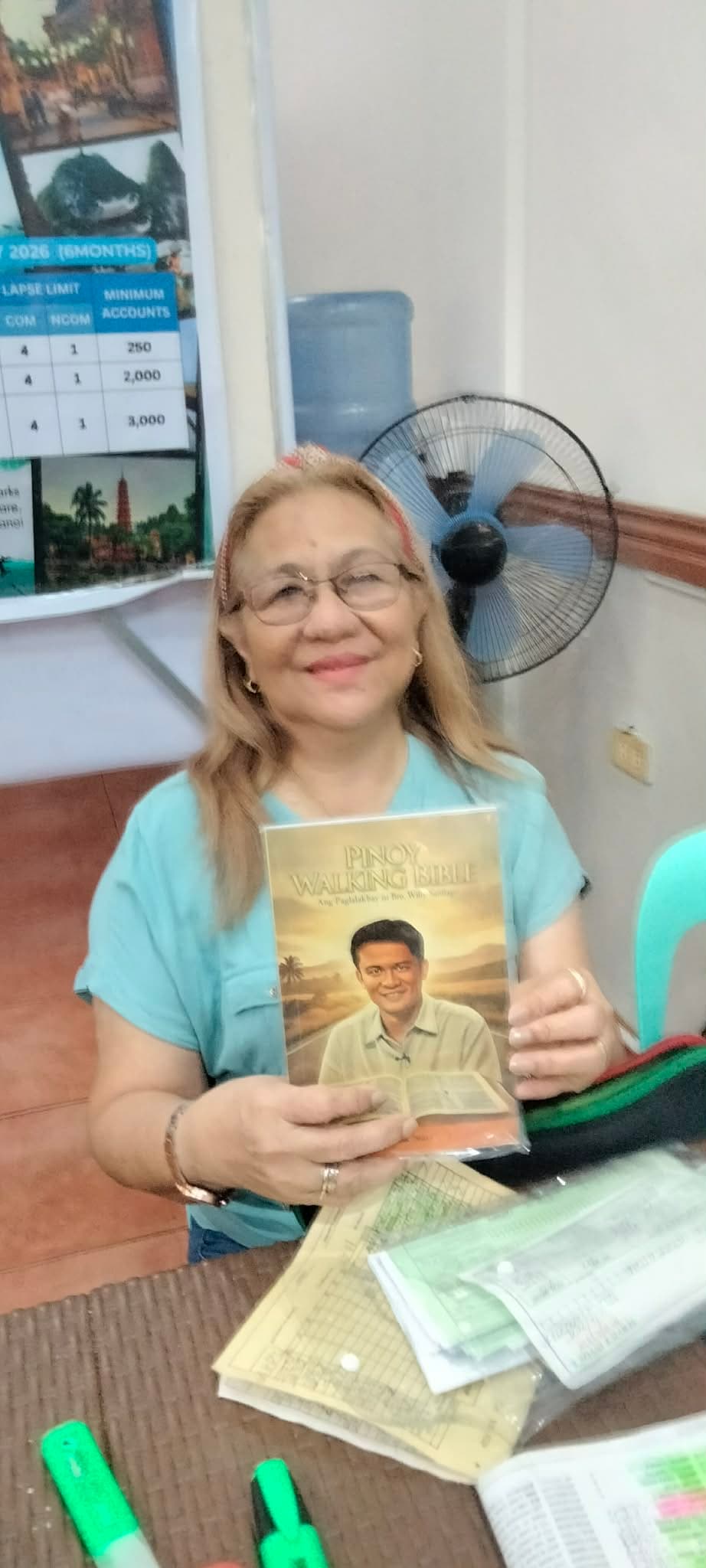 Supporter at a desk proudly displaying the Pinoy Walking Bible booklet