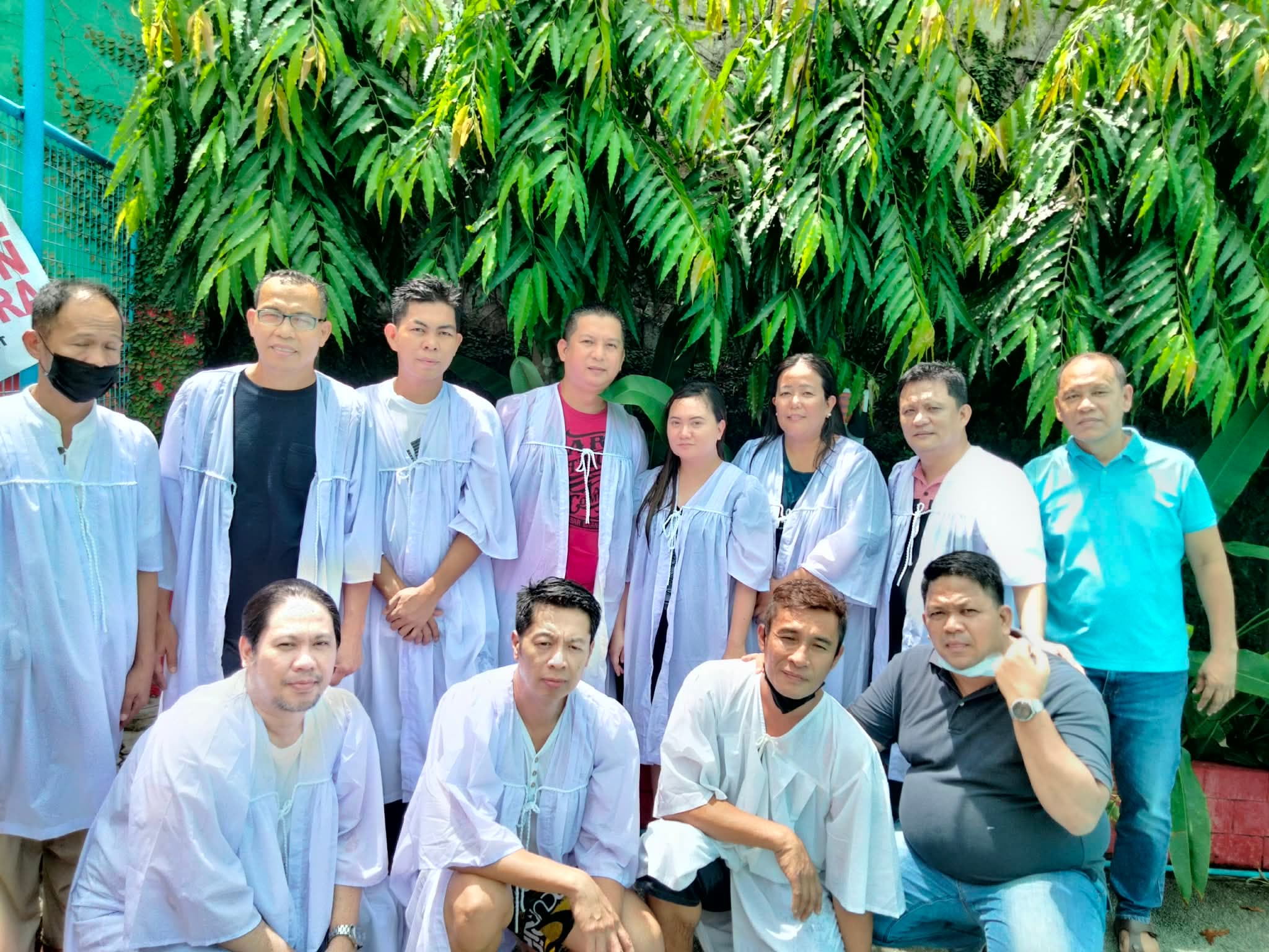 Ministers and candidates standing at the edge of the baptism pool in white robes